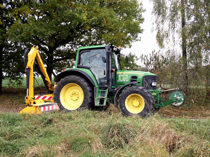 Traktor John Deere s příkopovým ramenem při sečení u cesty