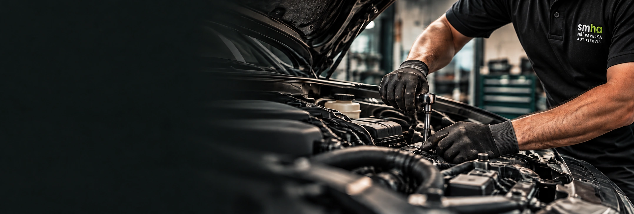 Mechanik autoservisu SM.HA v tričku s logem smha při opravě motoru
